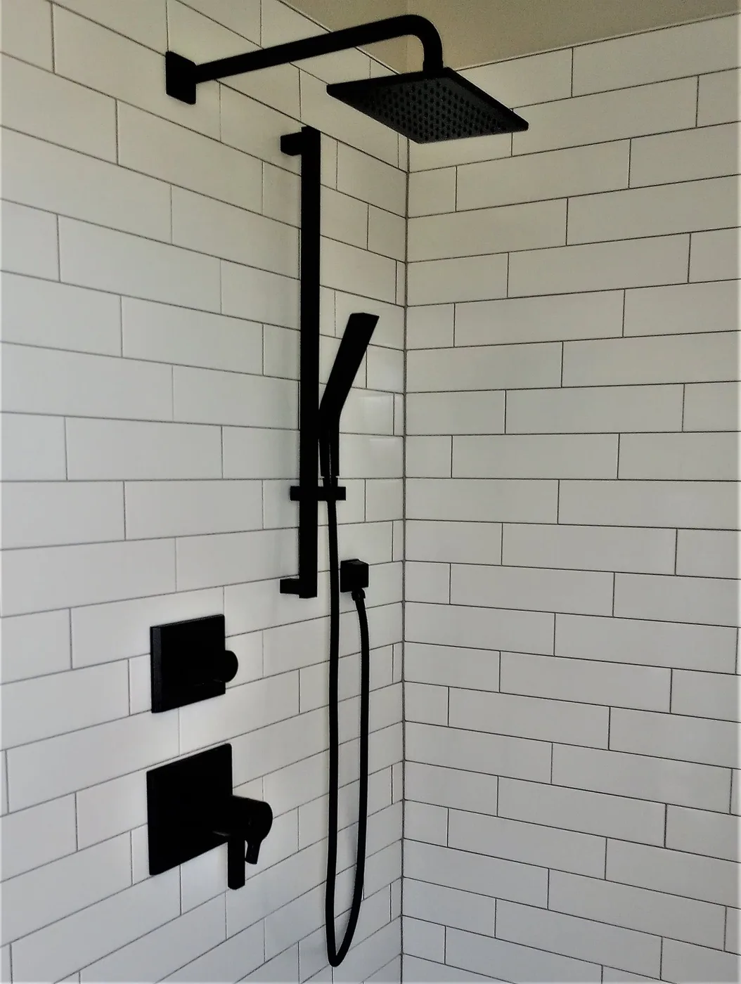 Matte black shower fixtures on white subway tile